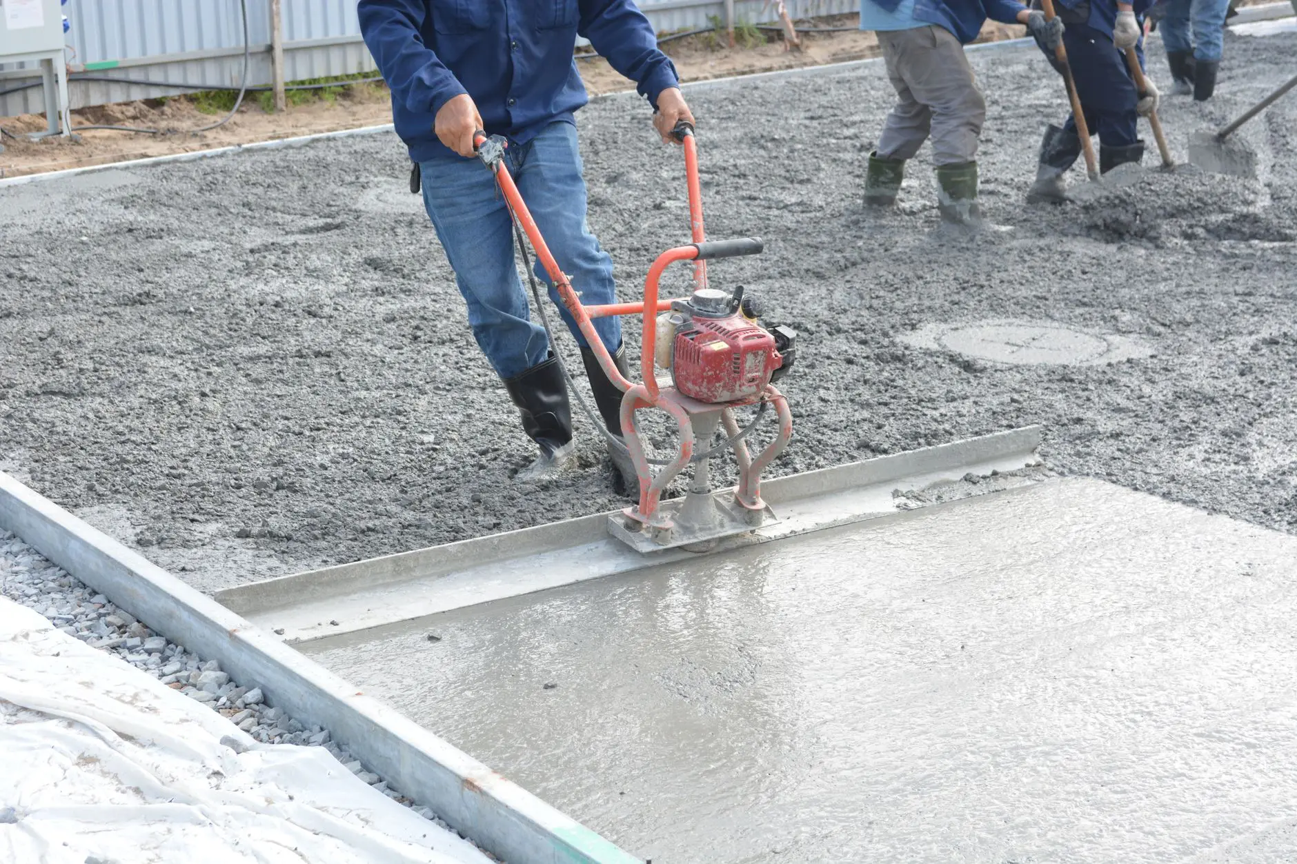 construction workers smoothing fresh concrete outdoors